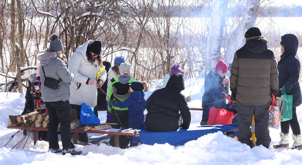 people gathered around an outdoor fire pit in the winter